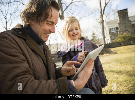 An Organic Farm in Winter in Cold Spring New York State A man holding a digital tablet in his hands showing his child the screen Stock Photo