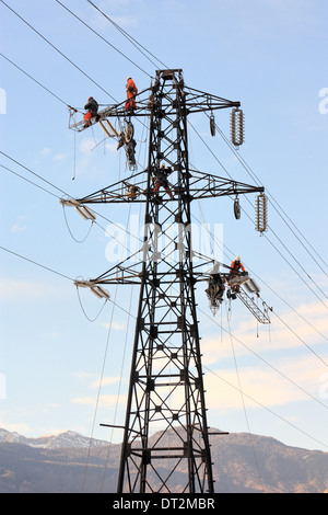 Workers at electricity pylons in Italy. Maintenance work of a high-voltage power line. Stock Photo