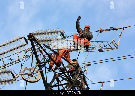 Workers at electricity pylons in Italy. Maintenance work of a high-voltage power line. Stock Photo