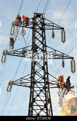 Workers at electricity pylons in Italy. Maintenance work of a high-voltage power line. Stock Photo