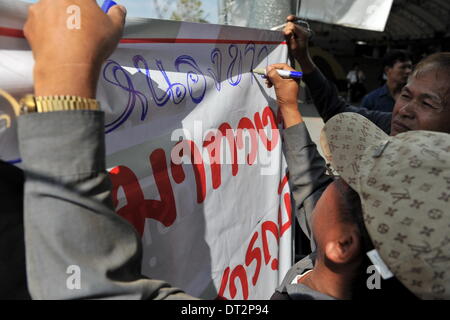 Bangkok, Thailand. 7th Feb, 2014. A Thai farmer writes slogans during a rally at the compound of Thailand's Commerce Ministry in Nonthaburi province, on the outskirts of Bangkok, Thailand, Feb. 7, 2014. Thai rice farmers who have gathered in protest of a delay in payments for their latest crop under the government's rice-pledging program on Friday drew a deadline for the government to pay before Feb. 15. Credit:  Gao Jianjun/Xinhua/Alamy Live News Stock Photo