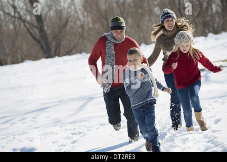 Winter scenery with snow on the ground Family walk Two adults chasing two children Stock Photo