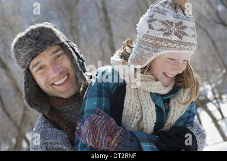 Winter scenery with snow on the ground A young girl with a bobble hat and scarf and a man hugging her