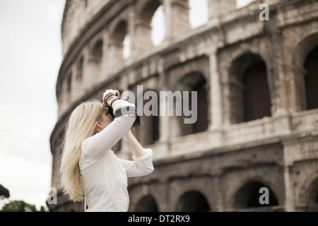 A woman outside the Colosseum amphitheatre in Rome taking photographs