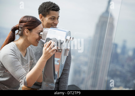 View over cityA young couple looking through the telescope Stock Photo