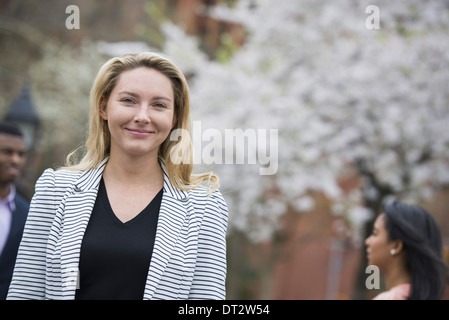 View over cityYoung people outdoors in a city park A woman in a grey jacket looking at the camera Stock Photo