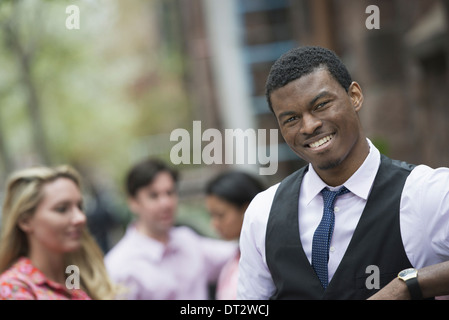View over cityYoung people outdoors in a city park A man smiling at the camera Three people behind him Stock Photo