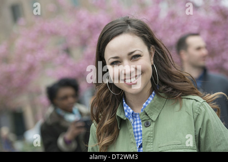 Cherry blossom trees in the park A young woman in an open necked shirt smiling and looking at the camera