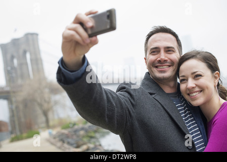 New York city The Brooklyn Bridge crossing over the East River A couple taking a picture with a phone a selfy of themselves