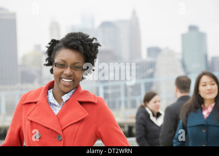 A cityscape view to Manhattan from Brooklyn Four people two in the background facing each other and two facing the camera Stock Photo