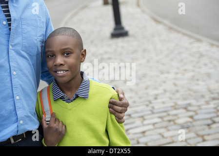 A boy holding a bag beside his father Stock Photo