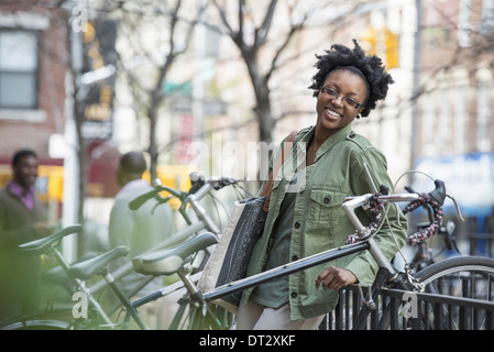 A woman leaning against a railing beside a bicycle rack Stock Photo