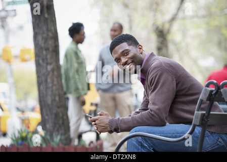 A young man on a bench and a group in the background Stock Photo