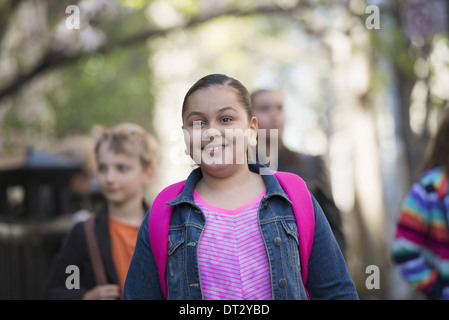 A group of children on the sidewalk with school bags or book bags Stock Photo