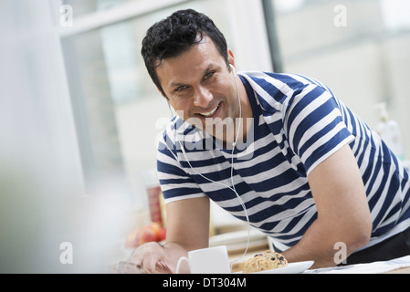 An office or apartment interior in New York City A man in a striped tee shirt leaning on the breakfast bar Stock Photo
