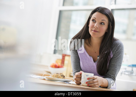 An office or apartment interior in New York City A young woman with long black hair having a cup of coffee Stock Photo