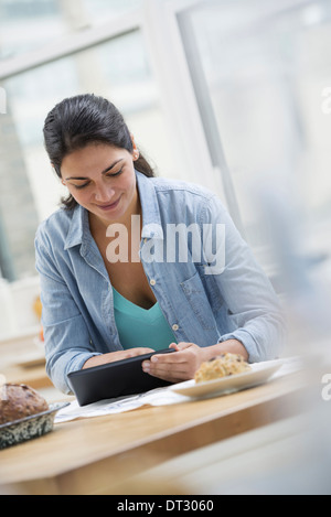 An office or apartment interior in New York City A young woman in a denim shirt using a digital tablet Stock Photo