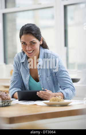 An office or apartment interior in New York City A young woman in a denim shirt using a digital tablet Stock Photo
