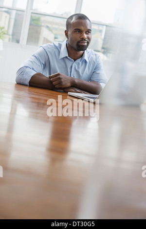 An office or apartment interior in New York City A man seated at a table using a laptop computer Stock Photo