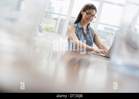 A young woman sitting comfortably in a quiet airy office environment Using a laptop Stock Photo