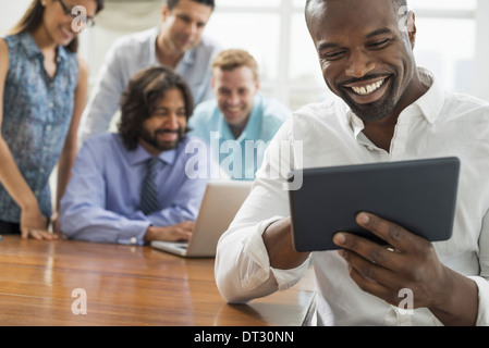 Business people gathered in an office in the city A team of five people men and women gathering around a laptop Stock Photo