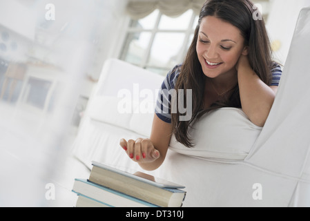 woman lying on her front on a sofa in a quiet airy office environment using a smart phone Stock Photo