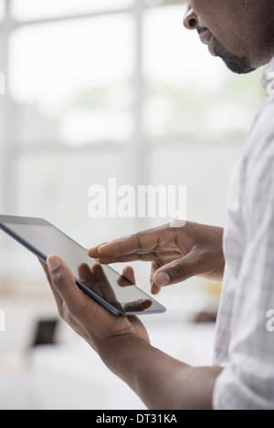 Professionals in the office A light and airy place of work A man in a white shirt using a digital tablet Stock Photo