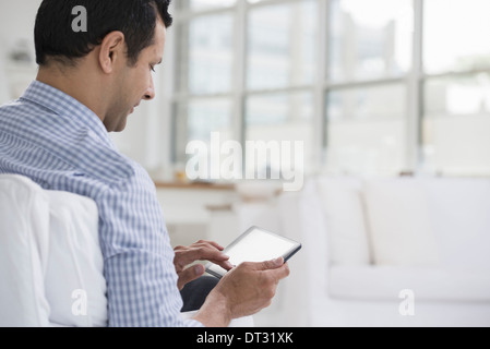 Professionals in the office A light and airy place of work A man seated using a digital tablet Stock Photo