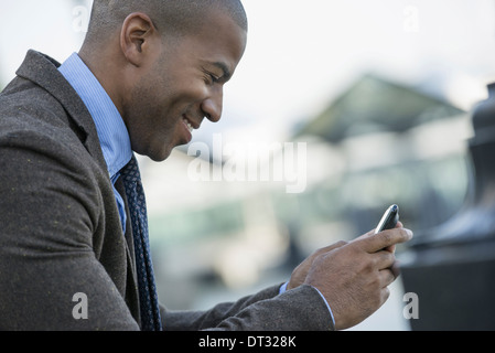 A man seated on a bench checking his smart phone Stock Photo