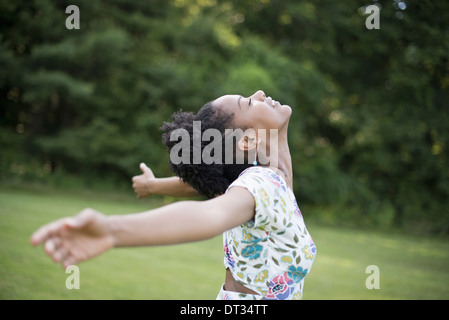 A young woman in a summer dress with her arms outstretched celebrating freedom