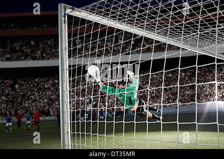 Goalie defending soccer net on field Stock Photo