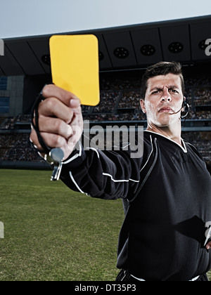 Referee flashing yellow card on soccer field Stock Photo