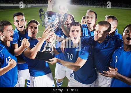 Soccer team cheering with trophy on field Stock Photo