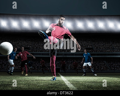 Soccer player kicking ball on field Stock Photo