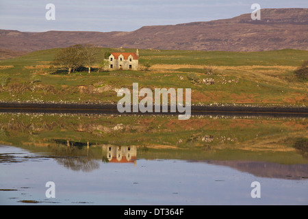 Old house on Ilse of Skye, Scotland, reflecting in the water of loch Stock Photo