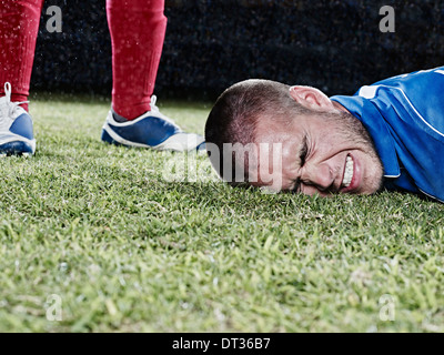 Soccer player falling on field Stock Photo