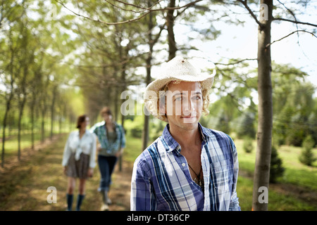 A group of friends walking down an avenue of trees in woodland Stock Photo