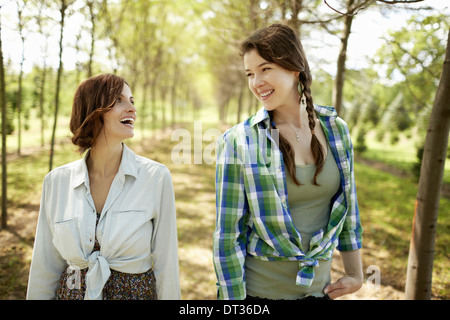 Two young women walking down an avenue of trees Stock Photo