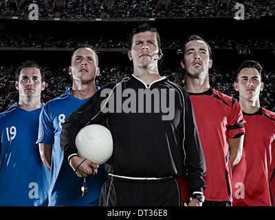 Soccer teams and referee standing in stadium Stock Photo