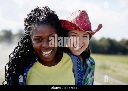 Two young women standing together with a sprinkler system working in the background Stock Photo