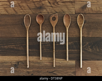 Home cooking. A wooden table with a varied wood grain and colour. Five wooden spoons in a row. Stock Photo
