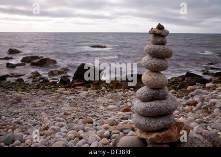 Rounded stones piled up on each other forming small statue on rocky beach in arctic Norway Stock Photo