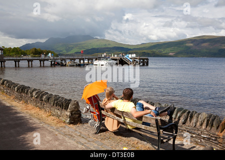 Couple enjoying the view across Loch Lomond, Luss, Argyll & Bute Stock Photo