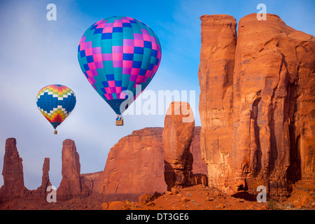 Hot air balloons drift past the Three Sisters and the Thumb rock formations, Monument Valley, Navajo Tribal Park, Arizona USA Stock Photo