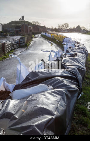 Flood defences at the village of Burrowbridge in Somerset on 8th February 2014. Due to high rainfall, the River Parrett has been unable to cope with the volume of water and has flooded nearby farmland leaving houses underwater. Here sand bags and ballast try to prevent The Riverside road from becoming submerged by Burrow Mump. A severe flood alert remains and some occupants have been told to evacuate. © Nick Cable/Alamy Live News Credit:  Nick Cable/Alamy Live News Stock Photo