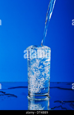 Puring water into the glass on blue Stock Photo