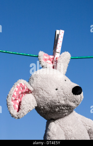 Soft toy mouse hanging on the washing line, against a blue sky background. Stock Photo