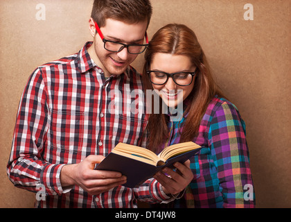 young couple in clothes and stylish hipster glasses reading a book. studio shot Stock Photo