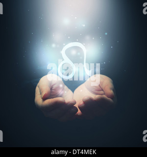 Female hands opening to light and holding zodiac sign for Leo. Horoscope symbols. Selective focus. Stock Photo