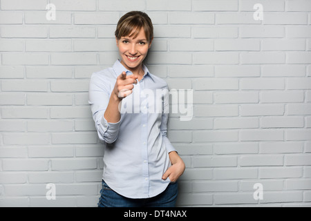 Female casual happy studio point fingers gray isolated background Stock Photo